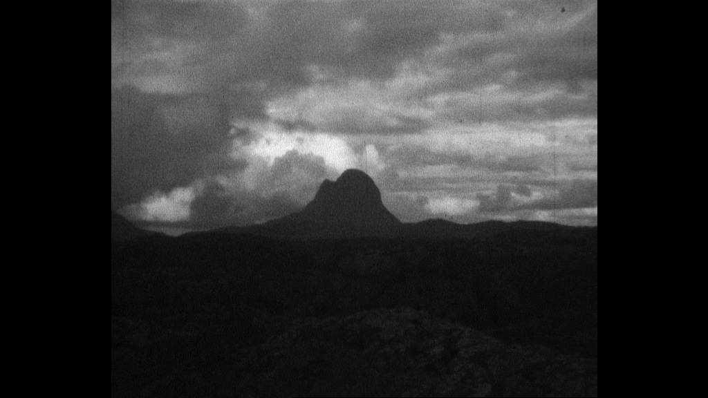 Black and white screen capture of a grainy film with mountain top in silhouette