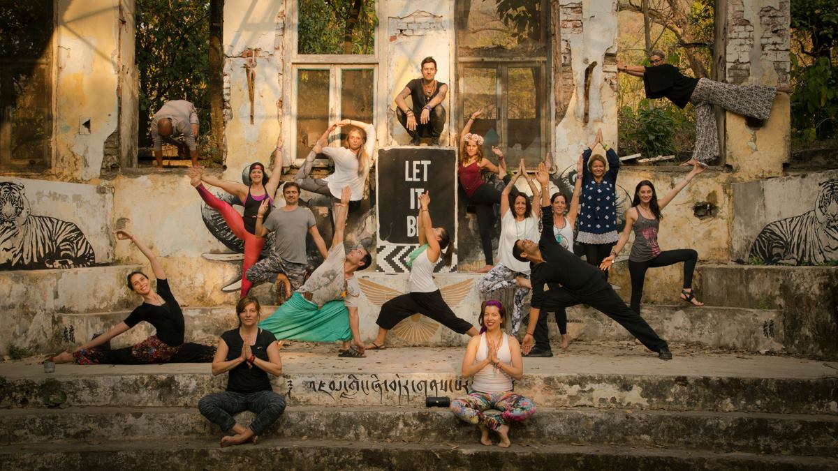 Group photo at the Beatles ashram in front of the Let it Be sigh. Most people in the photo are doing a yoga posture.